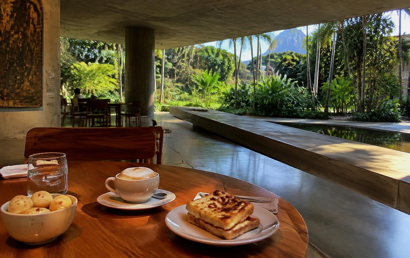 Mesa da Cantina do MAM com cappuccino, pão de queijo e croque, de frente para o jardim